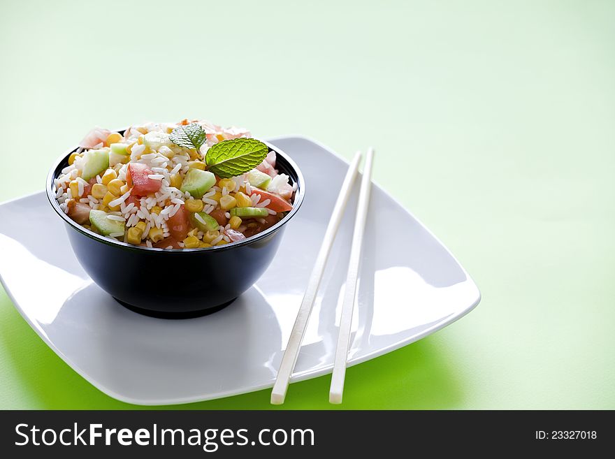 Photograph of a bowl of rice salad with corn tomato and cucumber