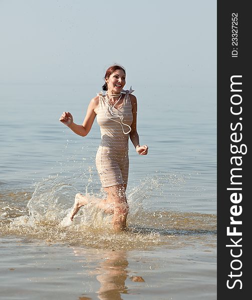 Woman in retro swimsuit smiles and runs through the water against the sea. Woman in retro swimsuit smiles and runs through the water against the sea