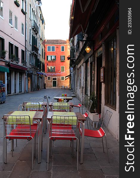 Urban scene. Few tables and chairs on narrow European street. Urban scene. Few tables and chairs on narrow European street