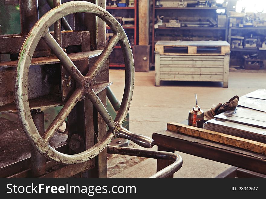 An old factory interior and a part of obsolete heavy machinery with control metal wheel. An old factory interior and a part of obsolete heavy machinery with control metal wheel