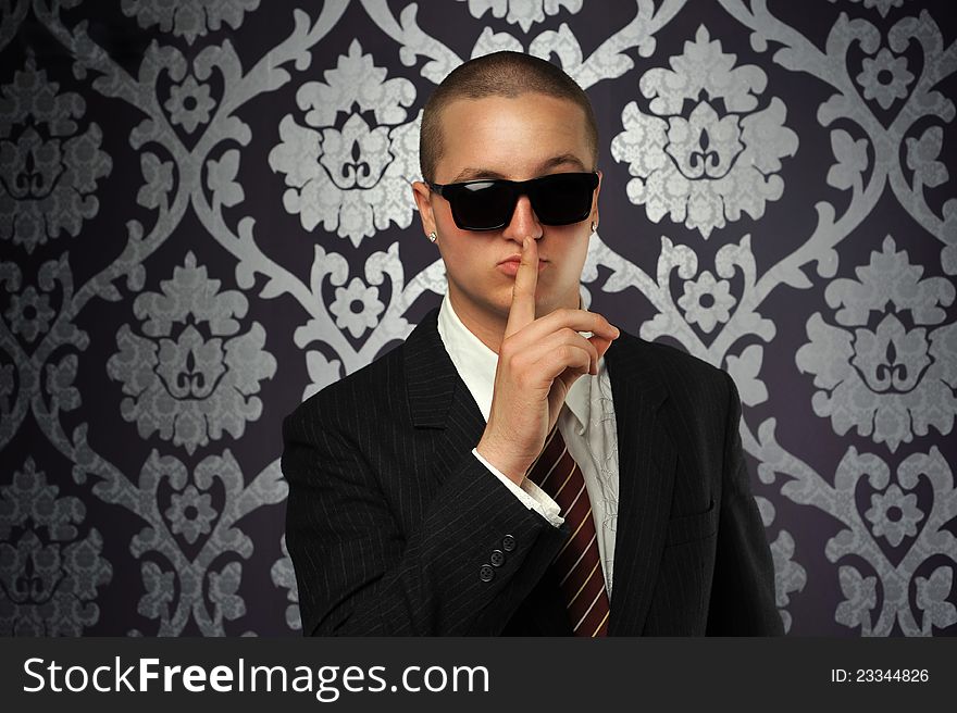 A hushing businessman with sunglasses