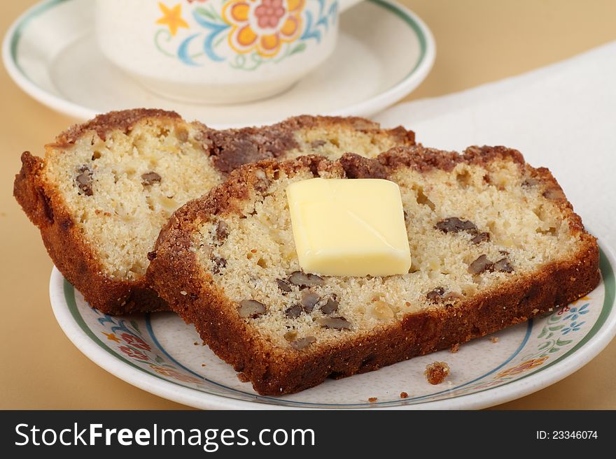 Two slices of nut bread with butter on a plate. Two slices of nut bread with butter on a plate