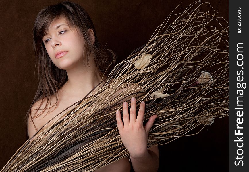 A portrait of a pretty young woman holding dried flowers and stems in front of herself. A portrait of a pretty young woman holding dried flowers and stems in front of herself