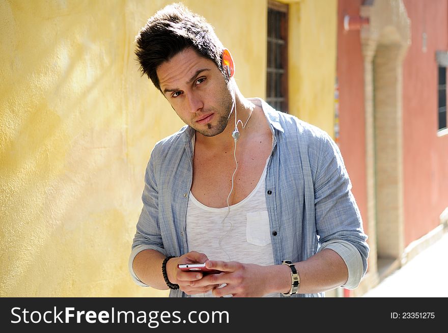 Portrait of handsome man in urban background listening to the music with headphones