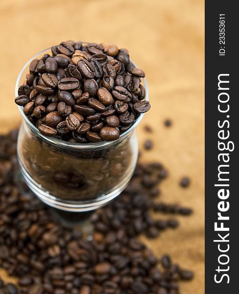 Grains of black roasted coffee in transparent cup