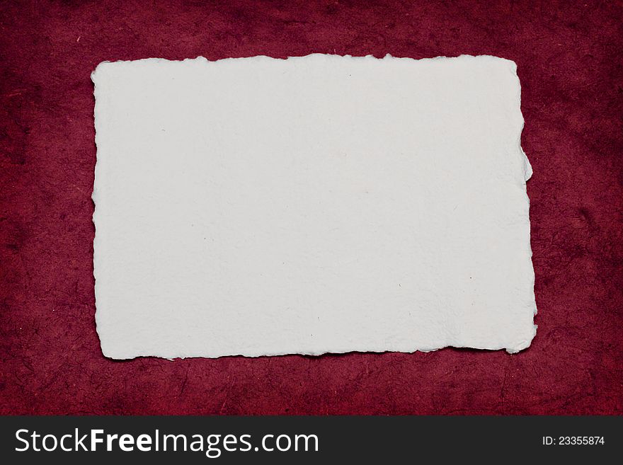 A torn piece of paper on a rough red background, perfect for a romantic invitation.