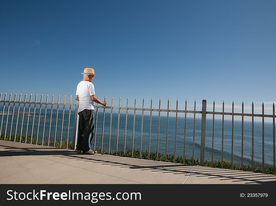 Senior man standing above the ocean looking out to sea