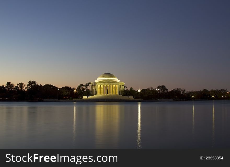 The Jefferson Memorial surrounded by cherry trees just minutes before sunrise. Its image and lights are reflecting off the water in the Tidal Basin. The Jefferson Memorial surrounded by cherry trees just minutes before sunrise. Its image and lights are reflecting off the water in the Tidal Basin.
