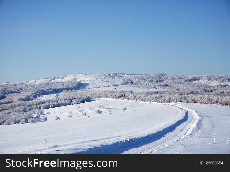 A winter scenery in the mountains with a road dug in high snow. A winter scenery in the mountains with a road dug in high snow