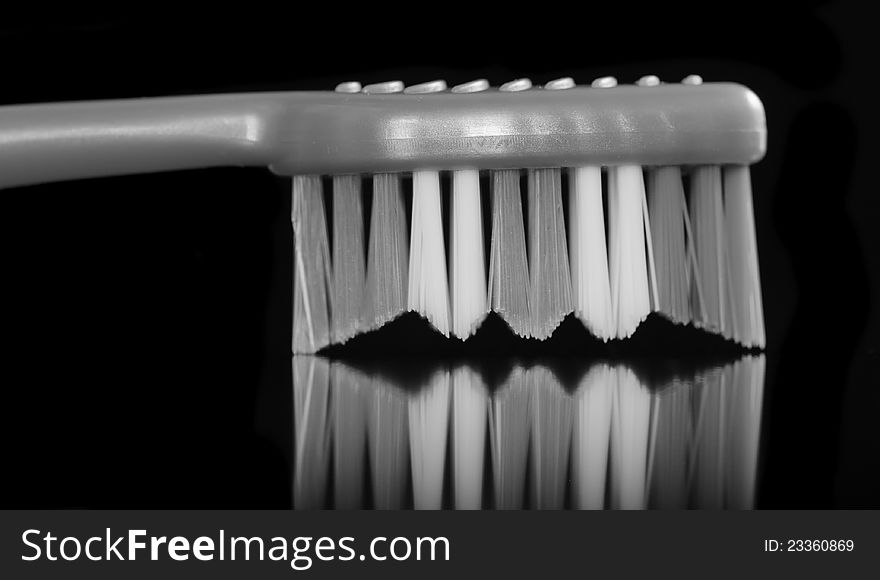A monochrome image of a toothbrush with bristles down on a black background. A monochrome image of a toothbrush with bristles down on a black background