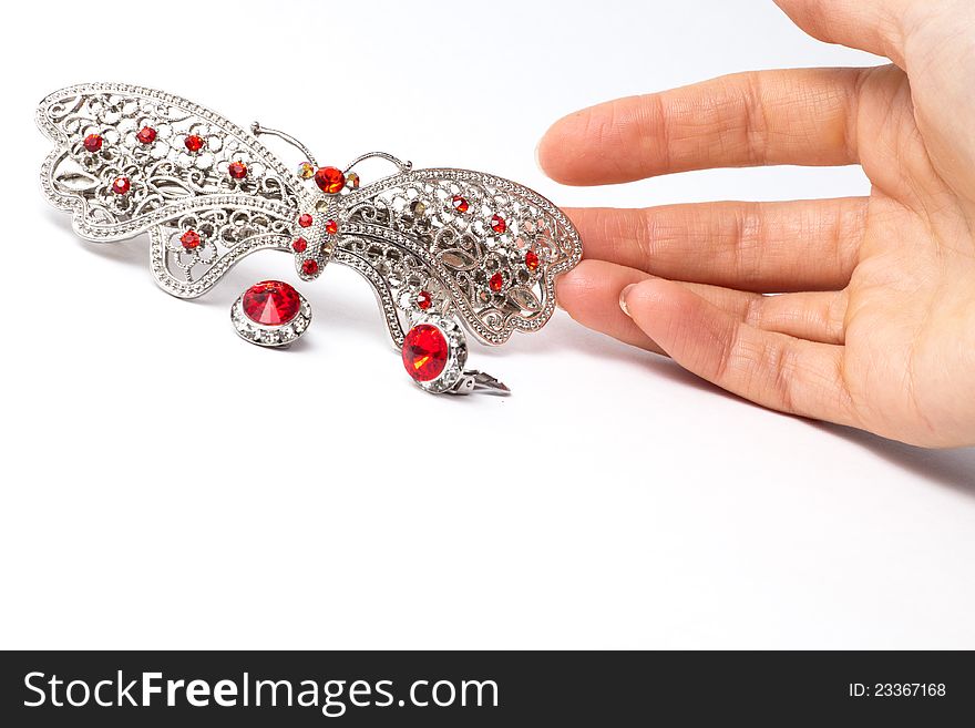 Jewelry in the form of butterfly with two ear clips and humans hand touching it on white background. Jewelry in the form of butterfly with two ear clips and humans hand touching it on white background
