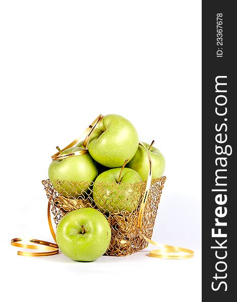 Green celebratory apples lie in a gold basket on a white background. Green celebratory apples lie in a gold basket on a white background