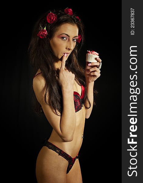 Young woman in red lingerie eating cake. Isolated on black. Low key. Young woman in red lingerie eating cake. Isolated on black. Low key