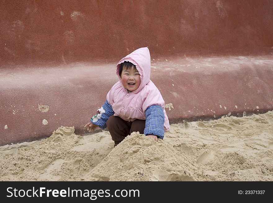 A happy girl is playing sand
