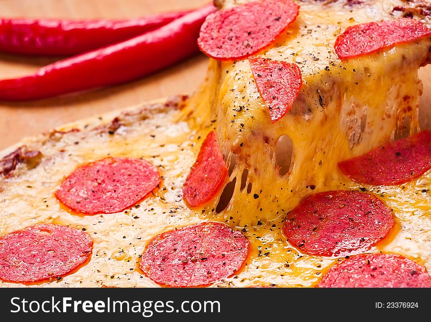 Cut pepperoni slice lifted above pizza