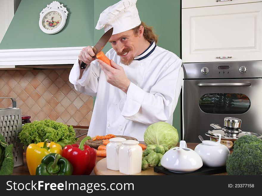 Funny young chef with carrot, preparing lunch in kitchen. Funny young chef with carrot, preparing lunch in kitchen