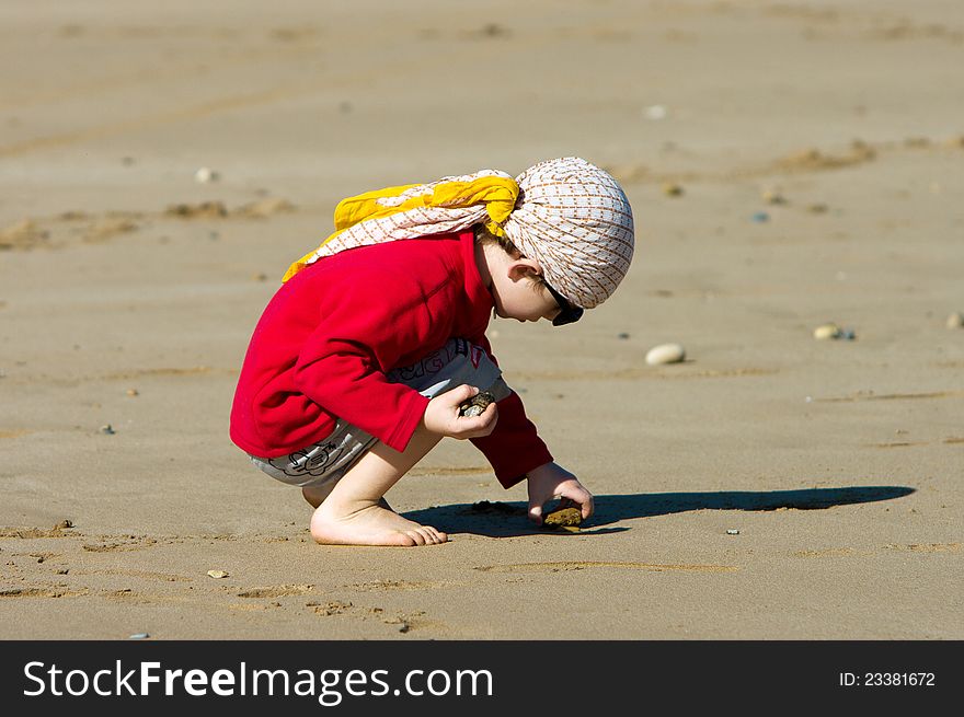 Little boy gathers stones on the ocean beach. Little boy gathers stones on the ocean beach