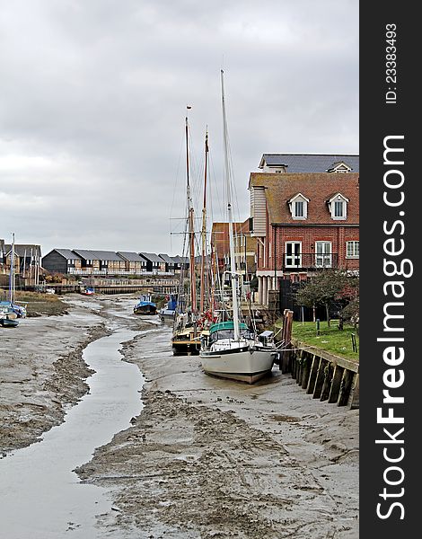 Photo of boats and yachts moored up on faversham creek at low tide. Photo of boats and yachts moored up on faversham creek at low tide.