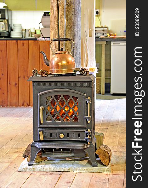 Photo of a copper kettle resting on top of a fire inside a country tea room. Photo of a copper kettle resting on top of a fire inside a country tea room.