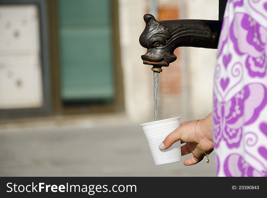 Filling a cup with water in the street