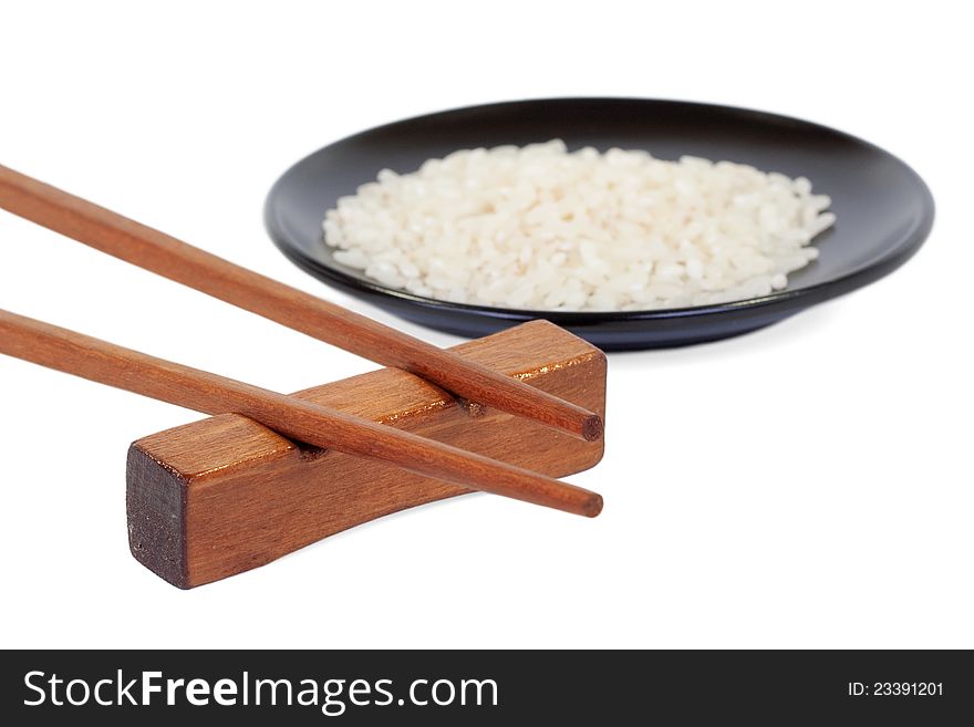 Wooden chopsticks and a black plate with rice on a white background. Wooden chopsticks and a black plate with rice on a white background