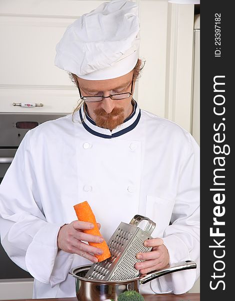 Young chef with carrot, preparing lunch in kitchen. Young chef with carrot, preparing lunch in kitchen