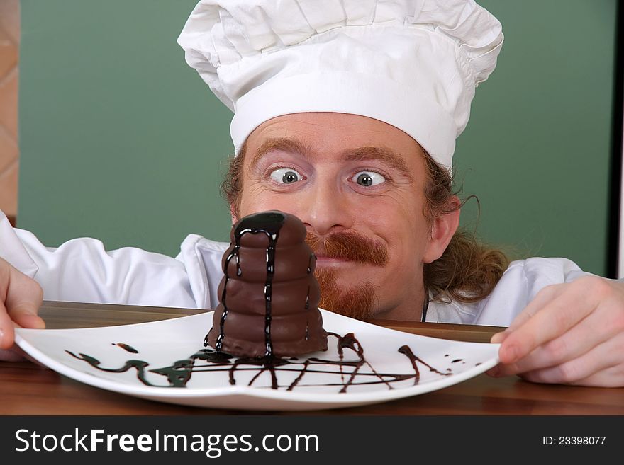 Funny young chef strange looking at piece of cake with chocolate sauce