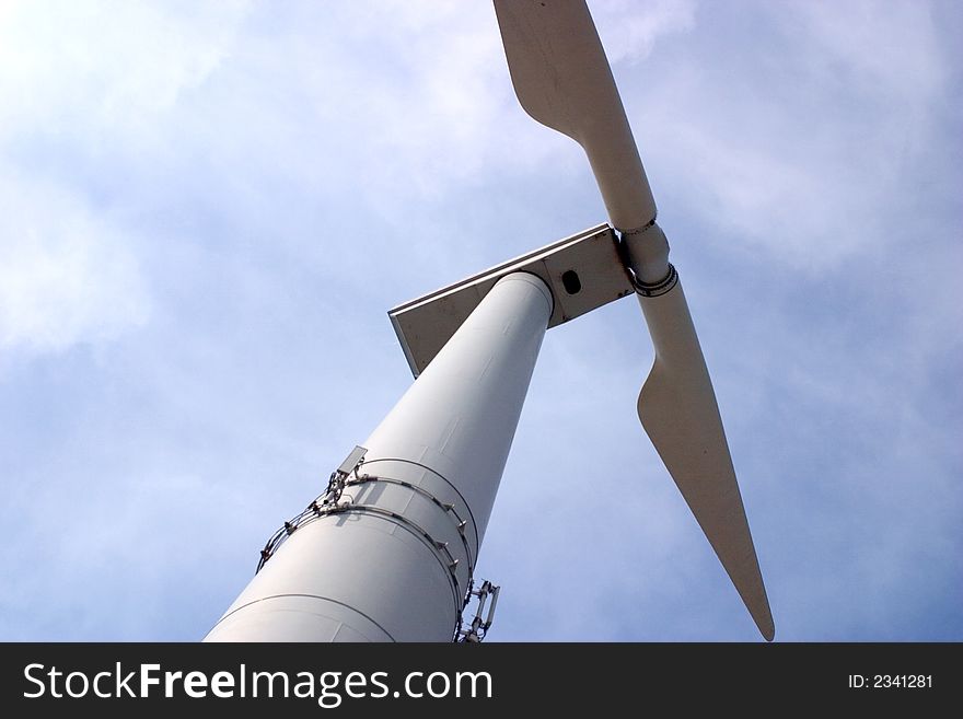 Wind turbine, photographed from an extreme angle, against a partly clouded sky