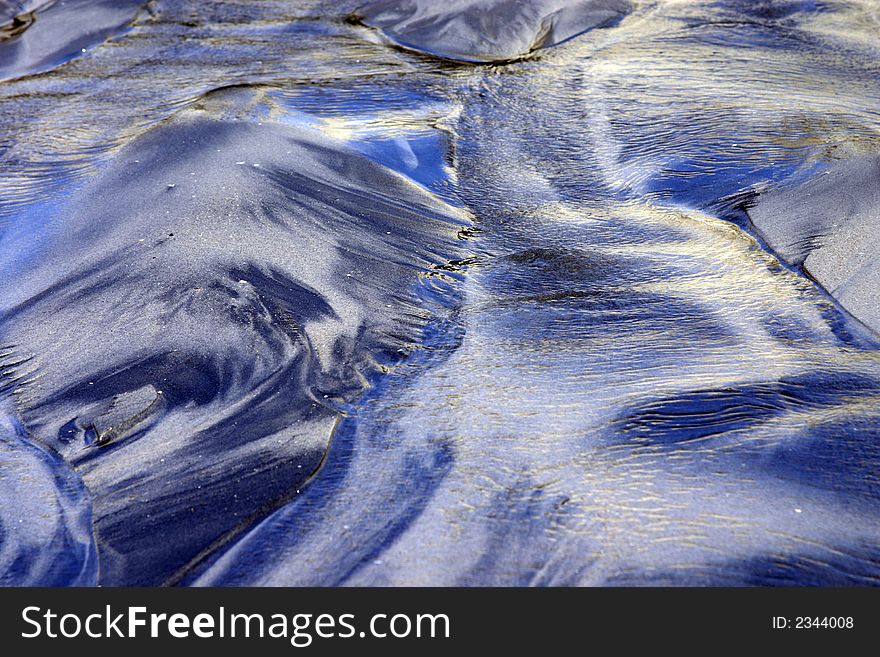 This is an image of sand on the beach that has been formed by wind, water, and natural elements. This is an image of sand on the beach that has been formed by wind, water, and natural elements.