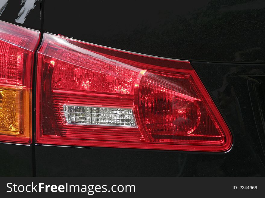 Car Detail - Red And White Rear Light Of A Black Automobile. Car Detail - Red And White Rear Light Of A Black Automobile
