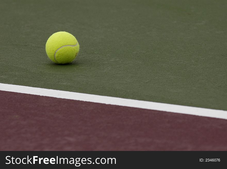 A lone tennis ball sitting a tennis court. A lone tennis ball sitting a tennis court.