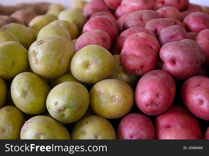 A large number of green and red potatoes stacked on a table beside each other