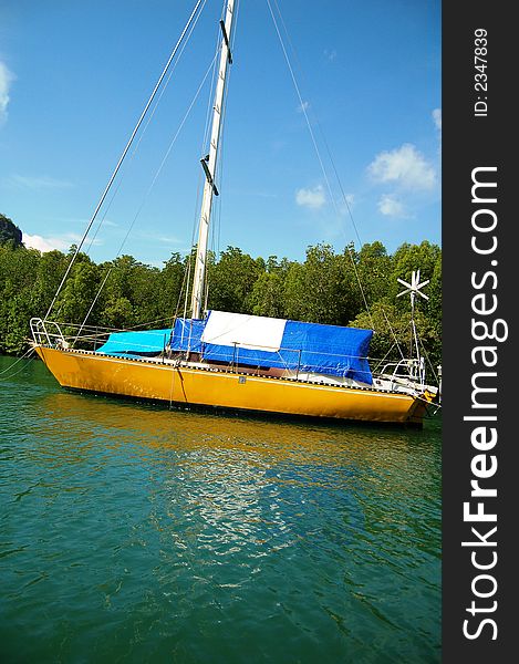 A catamaran anchored at the famous Kilim Geo-forest, Langkawi Island, Malaysia in clear water and mangrove forest as background. A catamaran anchored at the famous Kilim Geo-forest, Langkawi Island, Malaysia in clear water and mangrove forest as background.