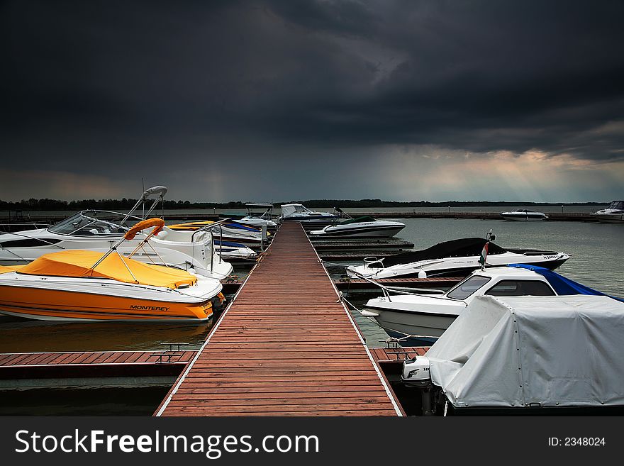 Boats in harbour under dark clouds
