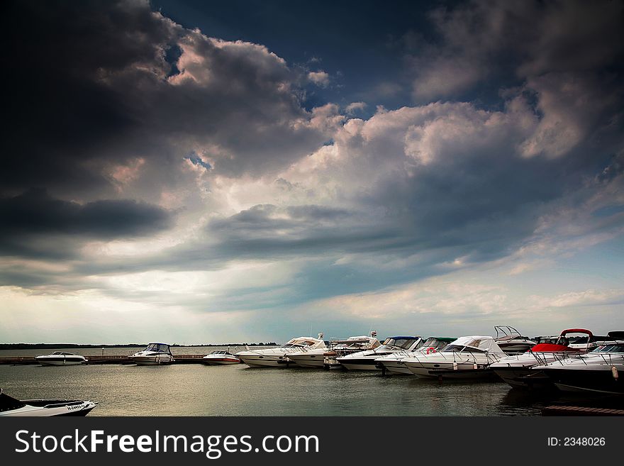 Boats in harbour under dark clouds