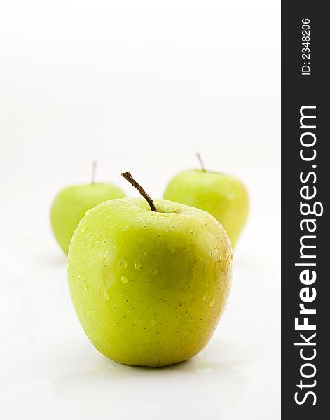 Fresh green apples over white background with water drops in perspective