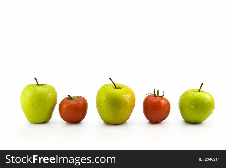 Fresh green apples and red tomatoes contrast in a row. Fresh green apples and red tomatoes contrast in a row