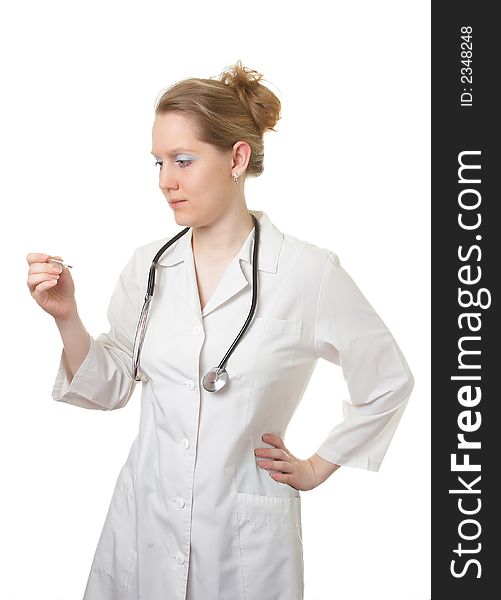 Woman the doctor in a white medical dressing gown with a stethoscope looks at a thermometer isolated on a white background. Woman the doctor in a white medical dressing gown with a stethoscope looks at a thermometer isolated on a white background