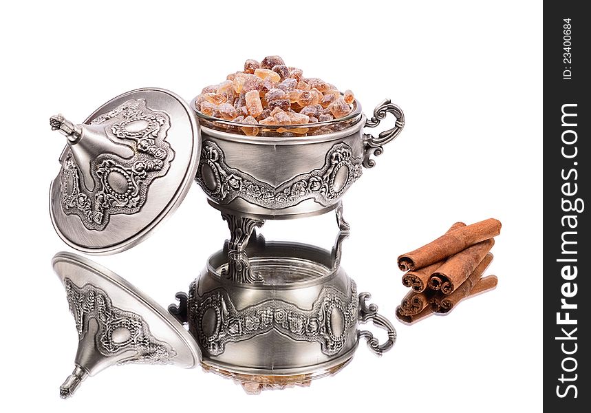 Brown sugar in, metal sugar bowl, reflection,cinnamon sticks