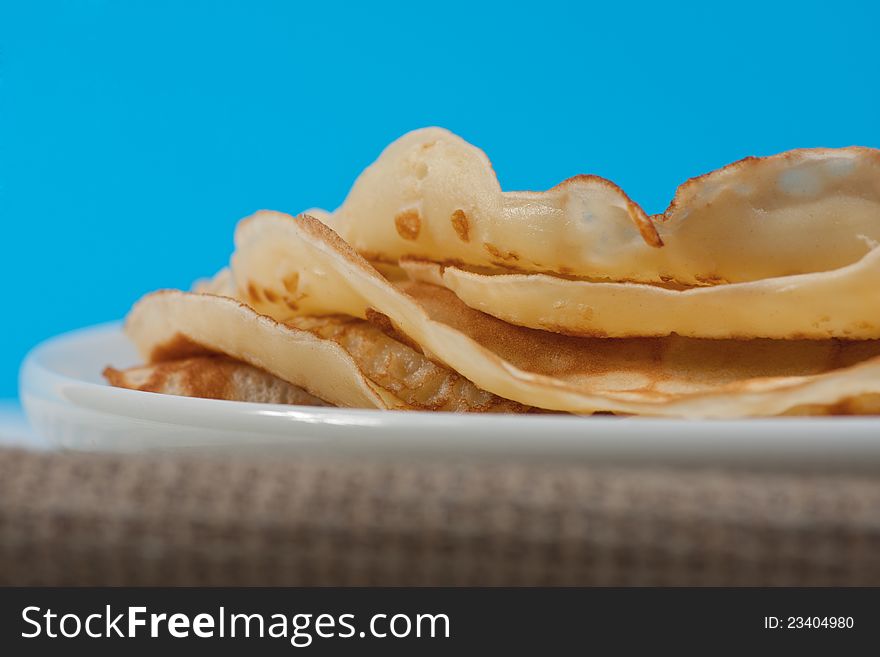 Pancakes on white plate. Blue background. Selective focus. Pancakes on white plate. Blue background. Selective focus.