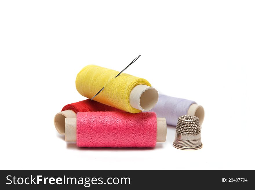 Color threads with needle and thimble on the white background