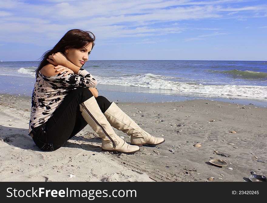 girl in boots sitting on the beach. girl in boots sitting on the beach