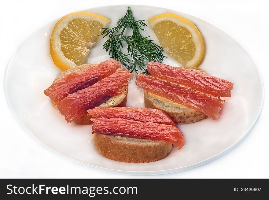 Sandwiches from a fillet red fish greens and a lemon on a plate on a white background