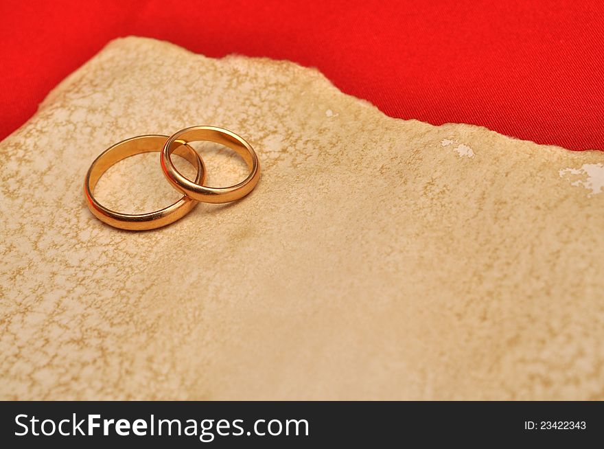 Wedding rings over aged grunge paper with red background. Wedding rings over aged grunge paper with red background
