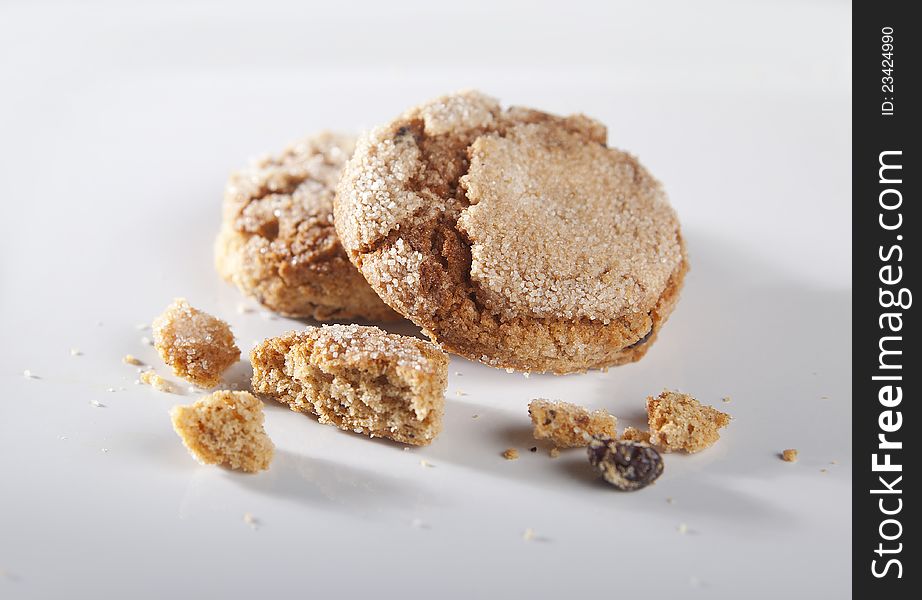 Two ginger cookies with risins and crumbs on the gray