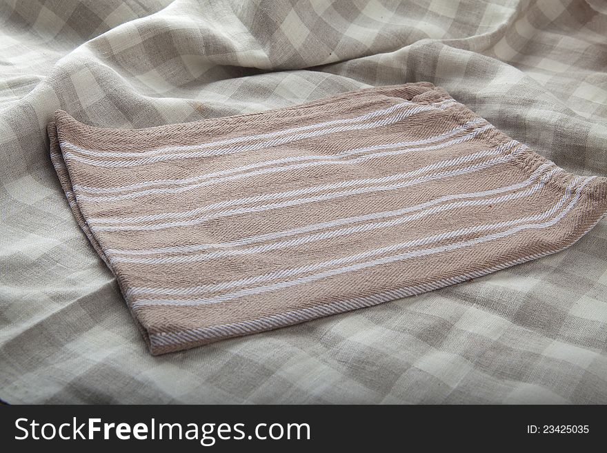 Cotton brown napkin on the folded tablecloth