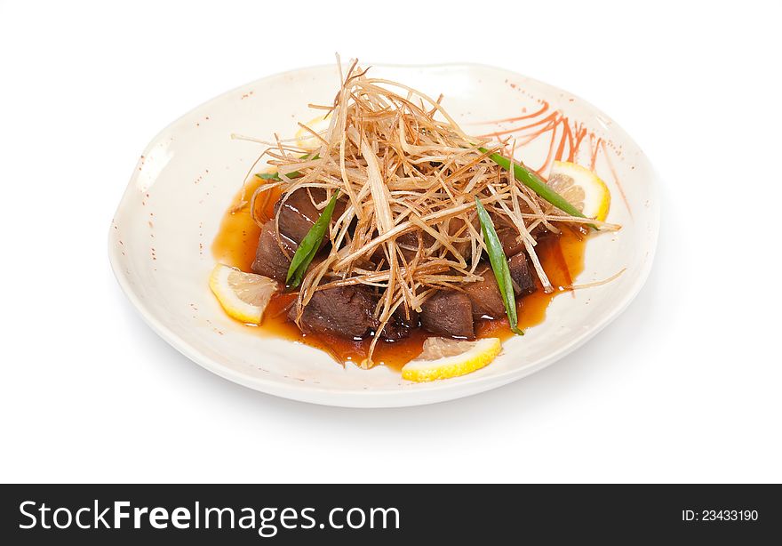 Slices of fried beef, sweet and sour sauce on a white plate on white background. Traditions of Japanese cuisine