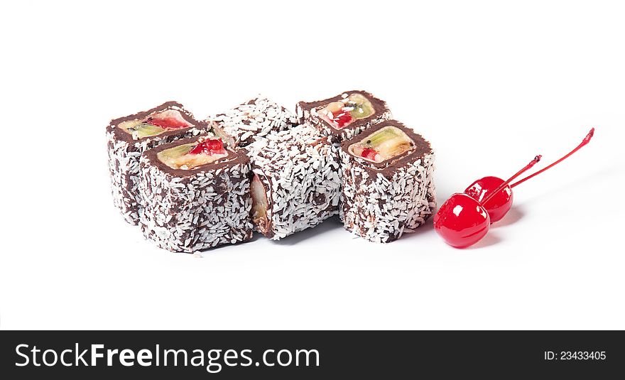 Chocolate roll with fruit filling sprinkle coconut with two cherries on a white background. The traditions of cuisine in Japan. Chocolate roll with fruit filling sprinkle coconut with two cherries on a white background. The traditions of cuisine in Japan