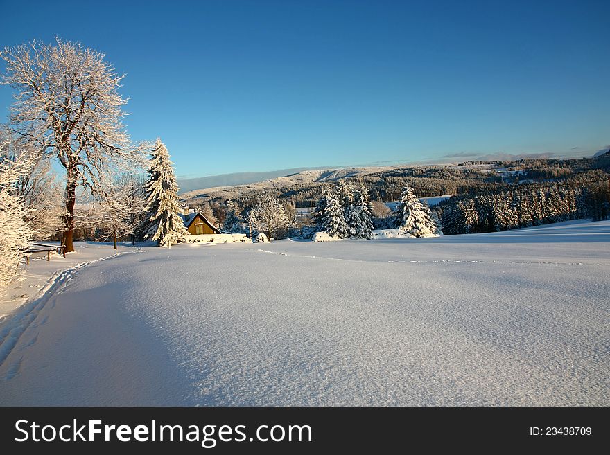 Picturesque winter landscape, winter landscape of the Eagle Mountains, sunny winter day in the landscape, snow-covered landscape in the setting sun, snow-covered cottage in the countryside. Picturesque winter landscape, winter landscape of the Eagle Mountains, sunny winter day in the landscape, snow-covered landscape in the setting sun, snow-covered cottage in the countryside