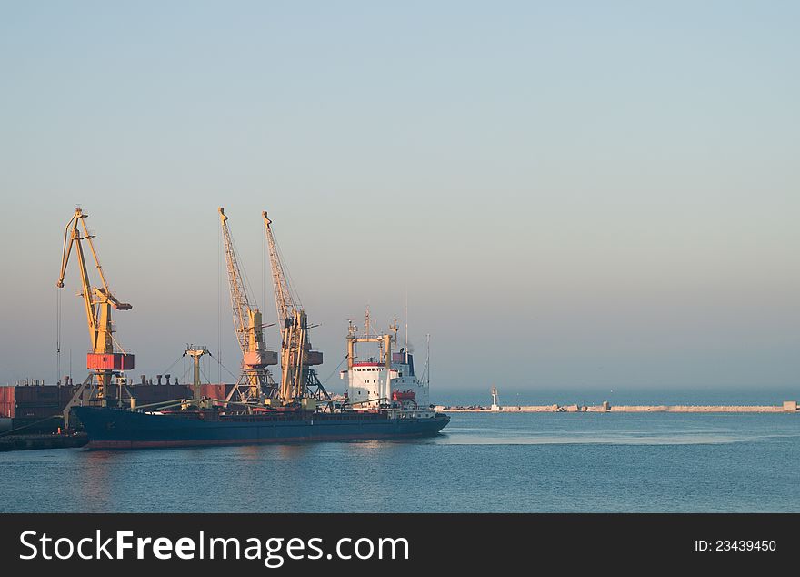 Commercial docks at sunset with a ship and cranes